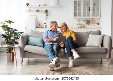 Cheerful Mature Spouses Using Digital Tablet Browsing Internet Or Watching Movie Together Sitting On Couch At Home. Senior People And Gadgets, Retirement Lifestyle Concept - Powered by Shutterstock