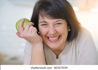 Cheerful Mature Woman Eating Green Apple