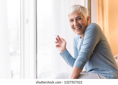 Cheerful Mature Woman Holding Cigarette In Her Hand And Looking At Camera With Beautiful Smile, Smoking Cigarettes Concept