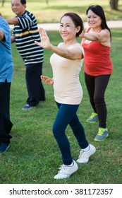 Cheerful Mature Woman Practicing Tai Chi In A Group