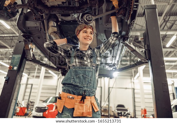 Cheerful mechanic with a tool belt gazing into\
the distance