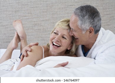 Cheerful Middle Aged Couple Lying In Bed