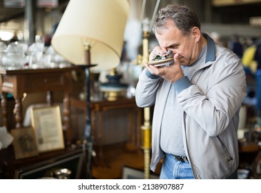 Cheerful Middle Aged Man Buying Retro Handicrafts On Indoor Flea Market