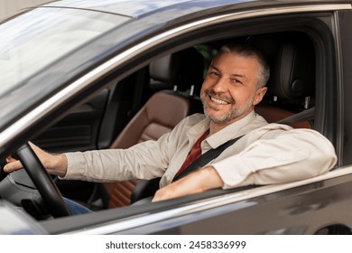 Cheerful middle aged man driving auto, looking through open window and smiling at camera, happy driver enjoying car ride - Powered by Shutterstock