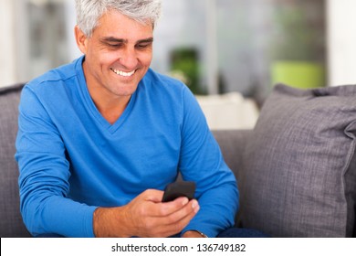 Cheerful Middle Aged Man Reading Emails On Smart Phone