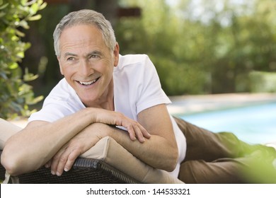 Cheerful Middle Aged Man Reclining On Deck Chair In Garden