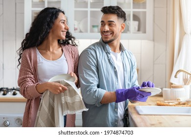 Cheerful Middle Eastern Couple Sharing Domestic Chores, Washing Dishes Together In Kitchen, Happy Millennial Arab Spouses Enjoying Making Cleaning At Home, Looking And Smiling To Each Other - Powered by Shutterstock