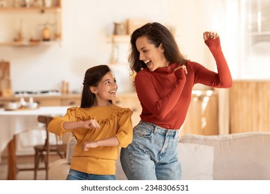 Cheerful Middle Eastern Mother And Daughter Kid Dancing Together At Modern Kitchen Interior. Young Mom And Preteen Child Girl Having Fun During Home Party Indoors On Weekend - Powered by Shutterstock