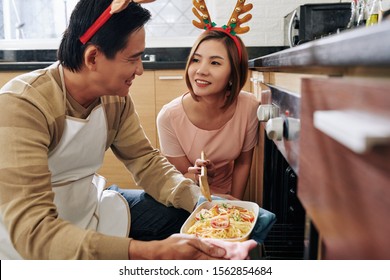 Cheerful Middle-aged Asian Couple Wearing Reindeer Antlers When Cooking Spaghetti For Christmas Dinner