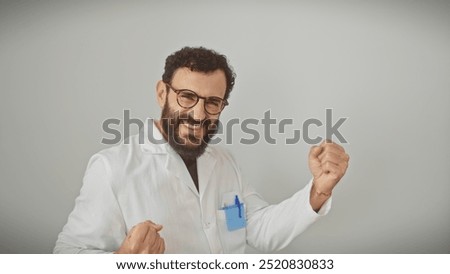 Cheerful middle-aged bearded man in labcoat celebrating success on white background