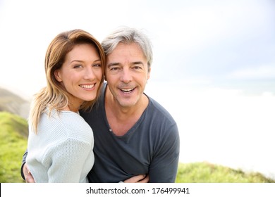 Cheerful middle-aged couple on the ocean coastline