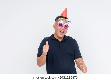 Cheerful middle-aged man wearing party hat and glasses giving thumbs up sign, celebrating and showing approval. Isolated on white. - Powered by Shutterstock