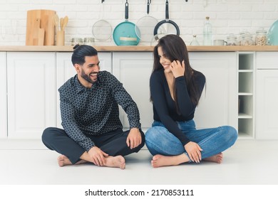 Cheerful Millenial Interracial Married Couple Sitting Barefoot On The Floor With Their Legs Crossed, Smilig And Talking Together. High Quality Photo