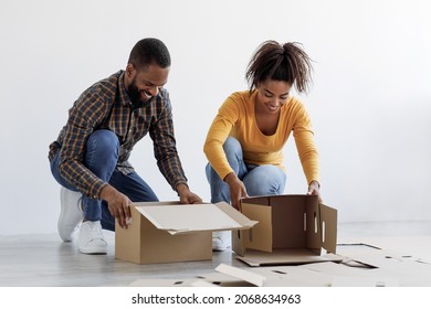 Cheerful Millennial African American Husband And Wife Stack Cardboard Boxes And Prepare To Move To New Home Relocation Together. Collecting Things For Moving To Apartment, Buying Real Estate And Rent