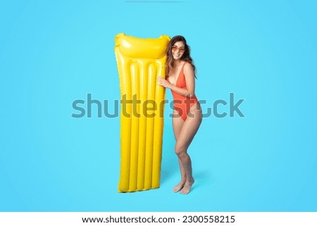 Cheerful millennial asian woman in swimsuit, sunglasses with inflatable mattress enjoy free time and swim in pool or sea isolated on blue studio background, full length. Summer fun, rest