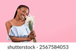 Cheerful millennial black lady holding bouquet of daffodils over pink studio background. Lovely millennial African American woman with bunch of narcissus flowers celebrating holiday