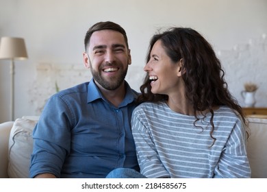 Cheerful Millennial Couple Home Head Shot Portrait. Happy Husband And Wife Sitting On Couch, Looking At Camera, Laughing, Talking On Video Call, Chatting. Communication, Relationship, Love Concept