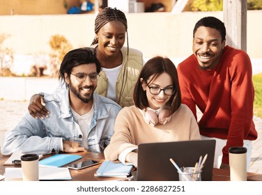 Cheerful millennial multiracial modern students look at computer, have video call, study together at university campus, outdoor. Knowledge, education, lesson remotely and lifestyle - Shutterstock ID 2286827251