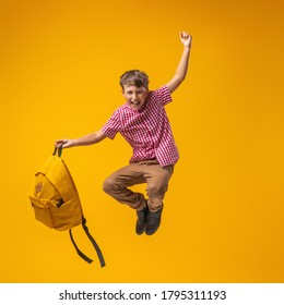 cheerful mischievous schoolboy in uniform with a backpack jumps on a yellow background. Dynamic images that go back to the school concept. beginning of holidays. Back to school. boy is ready to study. - Shutterstock ID 1795311193