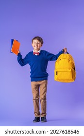 cheerful mischievous schoolboy in uniform with a backpack jumps on a purple background. Dynamic images that go back to the school concept. beginning of holidays. Back to school. boy is ready to study. - Shutterstock ID 2027618546