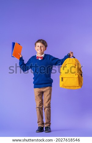 cheerful mischievous schoolboy in uniform with a backpack jumps on a purple background. Dynamic images that go back to the school concept. beginning of holidays. Back to school. boy is ready to study.