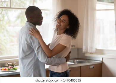 Cheerful mixed race couple in love having fun, dancing slowly at kitchen, feeling happy, enjoying weekend time, celebrating moving in new apartment or family special event, romantic dating concept. - Powered by Shutterstock