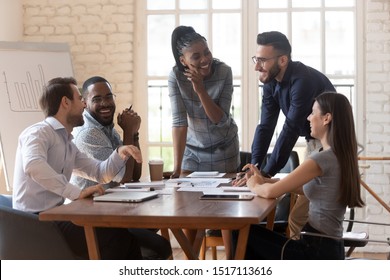 Cheerful mixed race young business partners enjoying break time during brainstorming meeting at office. Happy diverse colleagues laughing, having fun during discussing working issues in boardroom. - Shutterstock ID 1517113616