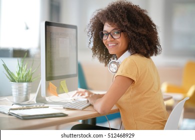 Cheerful mixed-race girl designing in office on desktop computer