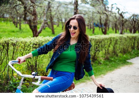 Cheerful modern hipster beautiful woman riding a retro bike in the city park. Rest in the open air. Active life