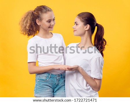 Cheerful Mom and daughter in a white T-shirt hug