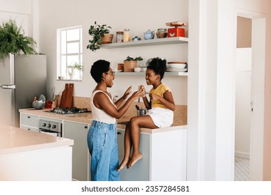 Cheerful mother and daughter playing a hand clapping game together, laughing and having fun in their home kitchen. Woman cherishing the joy of parenthood and the bond between her and her child. - Powered by Shutterstock