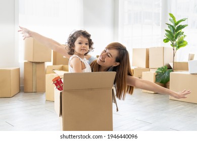 Cheerful Mother And Her Little Toddler Daughter Playing Inside Cardboard Box While Moving Into New Home With Cardboard Boxes On Background