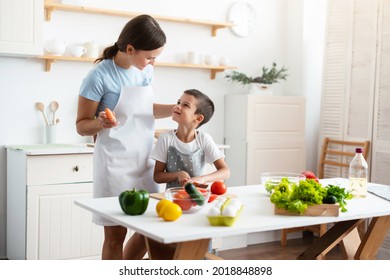 Cheerful mother proud her self-dependent son. Child unaided is cooking salad at kittchen. Healthy food concept. - Powered by Shutterstock