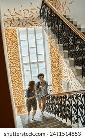 cheerful multicultural students talking while walking on staircase with colorful walls in hostel
