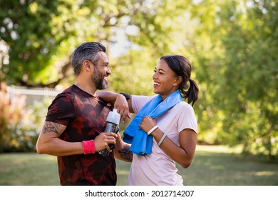 Cheerful multiethnic couple resting together after jogging in the park. Happy mature man and beautiful woman laughing while resting after running. Woman and indian man taking a break after fitness. - Shutterstock ID 2012714207