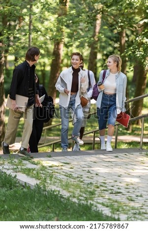 Cheerful multiethnic students talking while walking in park