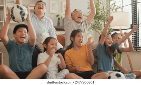 Cheerful multi-generation asian family having fun while watching a game of their favorite sports team on TV at home happy exciting Family cheering football soccer in living room at home  - Powered by Shutterstock