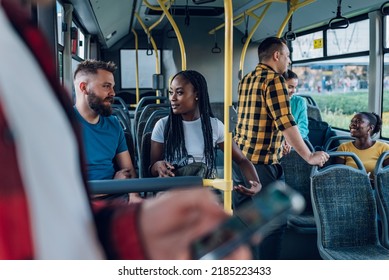 Cheerful multiracial friends smiling and talking together while riding in a city bus. Public transport, commuting by bus. Diverse couple. Focus on a beautiful african american woman. - Powered by Shutterstock