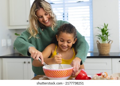 Cheerful multiracial mother teaching cute daughter to mix batter with wire whisk in bowl in kitchen. Happy, unaltered, family, togetherness, childhood, food, preparation, learning, lifestyle, home. - Powered by Shutterstock