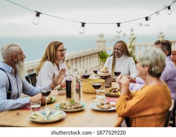 Cheerful multiracial senior friends having fun at a dinner outdoor on patio - Powered by Shutterstock