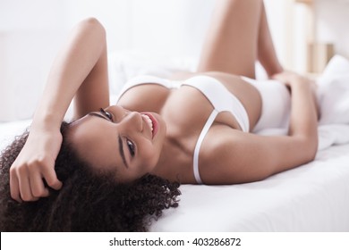 Cheerful multiracial woman is luxuriating on couch