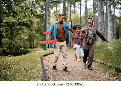 Cheerful Muslim Parents Having Fun With Their Daughter While Walking In The Park. Copy Space. 