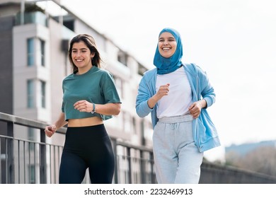 Cheerful muslim woman wearing hijab running in the street with her friend and having fun. - Powered by Shutterstock