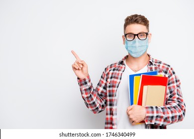 Cheerful Nerd Student Holding Book And Educational Materials Pointing On A Copyspace Showing Information Idea Wear Medical Safety Face Mask, Remote Distance Online Education Concept