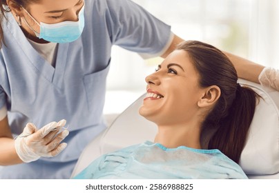 Cheerful nurse or doctor orthodontist conducting an oral checkup on a happy female patient using dental instruments in the clinic. Comprehensive dental care provided by the dentist.