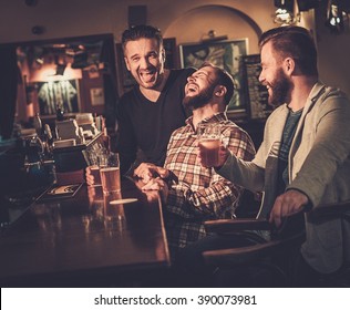 Cheerful Old Friends Having Fun And Drinking Draft Beer At Bar Counter In Pub.