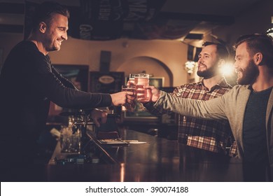 Cheerful Old Friends Having Fun And Drinking Draft Beer At Bar Counter In Pub.