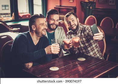 Cheerful Old Friends Having Fun Taking Selfie And Drinking Draft Beer In Pub.