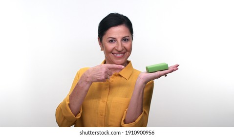 Cheerful Old Lady Holding Small Green Box In Hand And Pointing With Her Finger, Isolated On White Background. Creative People Can Put The Product They Want In The Woman's Hand.