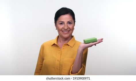 Cheerful Old Lady Holding Small Green Box In Hand And Pointing With Her Finger, Isolated On White Background. Creative People Can Put The Product They Want In The Woman's Hand.